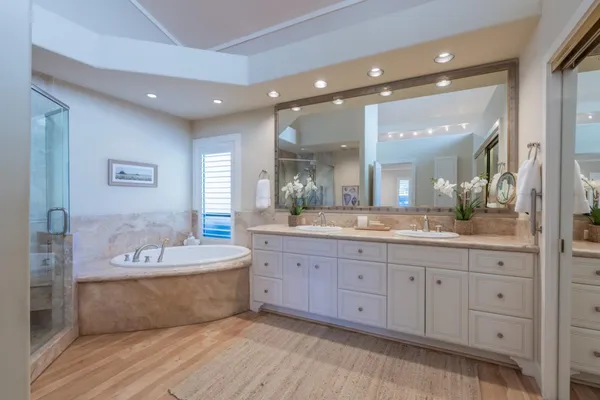 a spacious bathroom with a double vanity sink mirror and bathtub