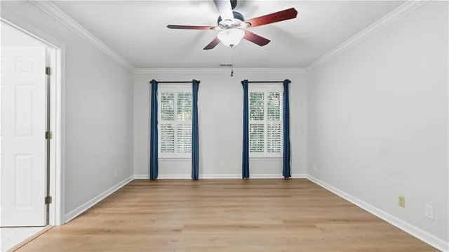 a view of an empty room with wooden floor and windows