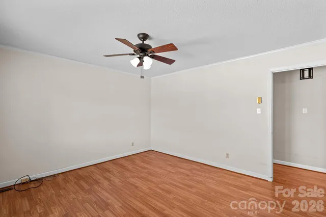 an empty room with wooden floor fan and windows
