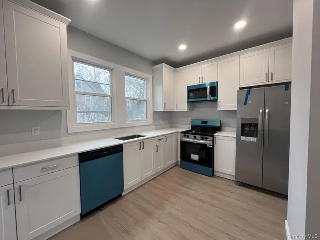 a kitchen with granite countertop a refrigerator stove top oven and sink