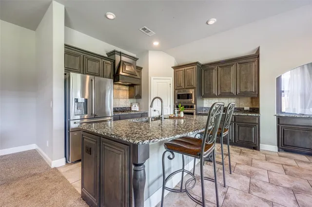 a kitchen with stainless steel appliances granite countertop a stove top oven a sink refrigerator and cabinets