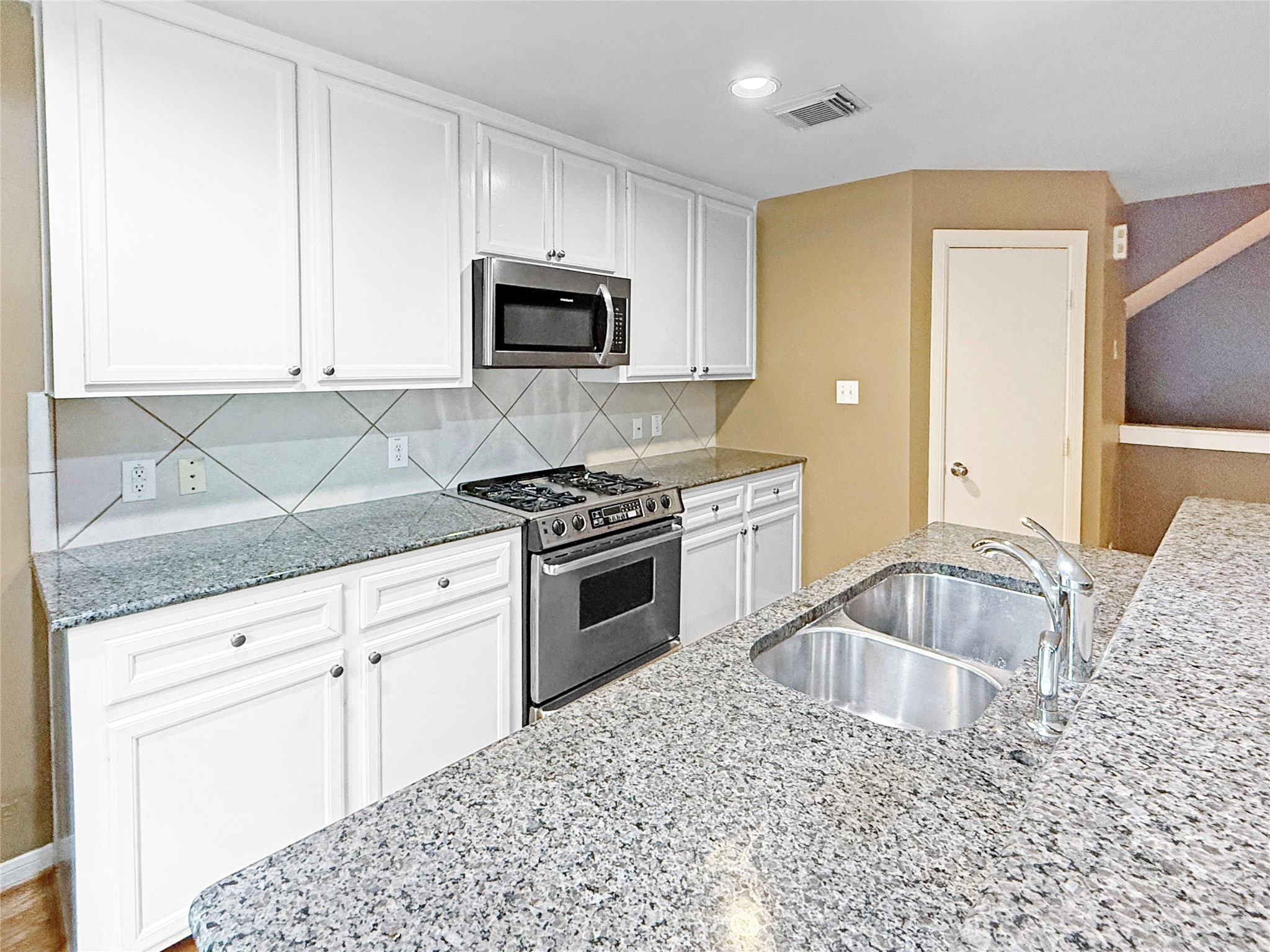 1263 West 17th Street Houston, TX 77008 - Photo 4 of 17 a kitchen with granite countertop white cabinets stainless steel appliances and a sink