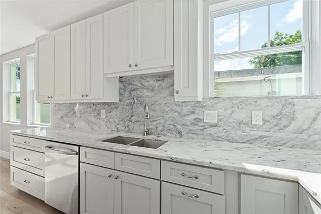 a kitchen with white cabinets and a window