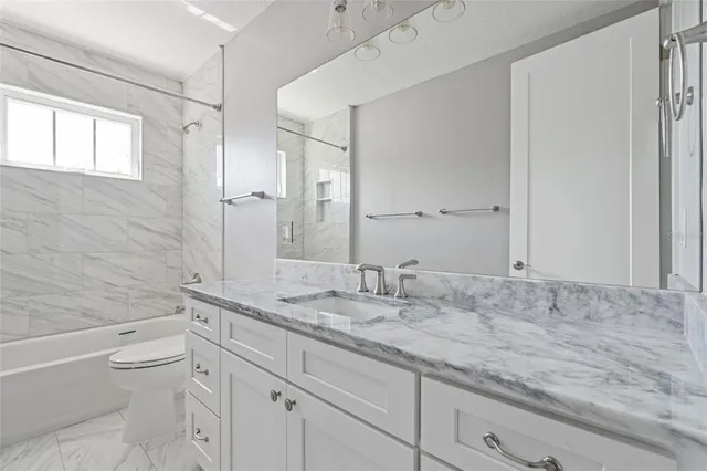 a bathroom with a granite countertop sink a toilet and bathtub