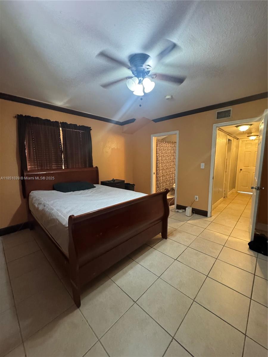 19550 Southwest 103rd Court, Unit 5 Cutler Bay, FL 33157 - Photo 23 of 28 a bedroom with a bed and a chandelier