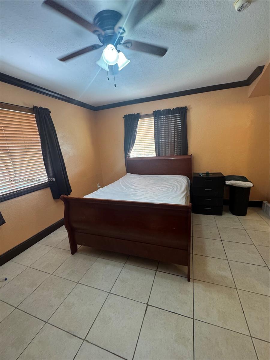 19550 Southwest 103rd Court, Unit 5 Cutler Bay, FL 33157 - Photo 27 of 28 a bedroom with a bed and a chandelier