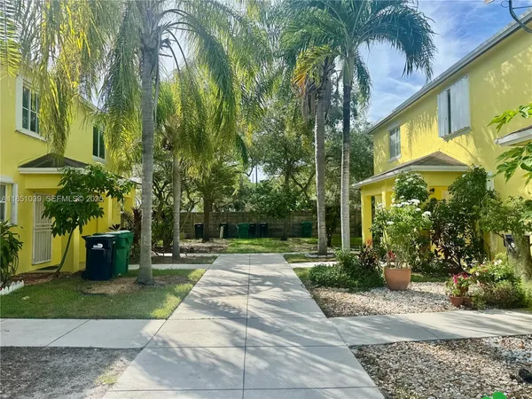 a pathway of a park with plants and palm trees