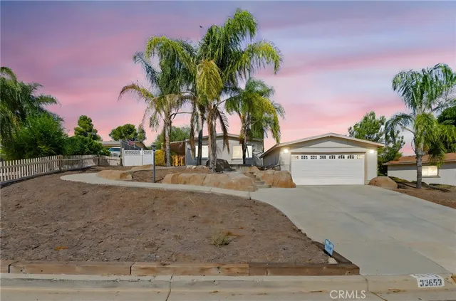 a view of a house with a yard and palm trees
