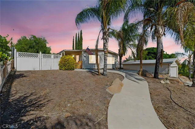 a view of a house with a yard and palm trees