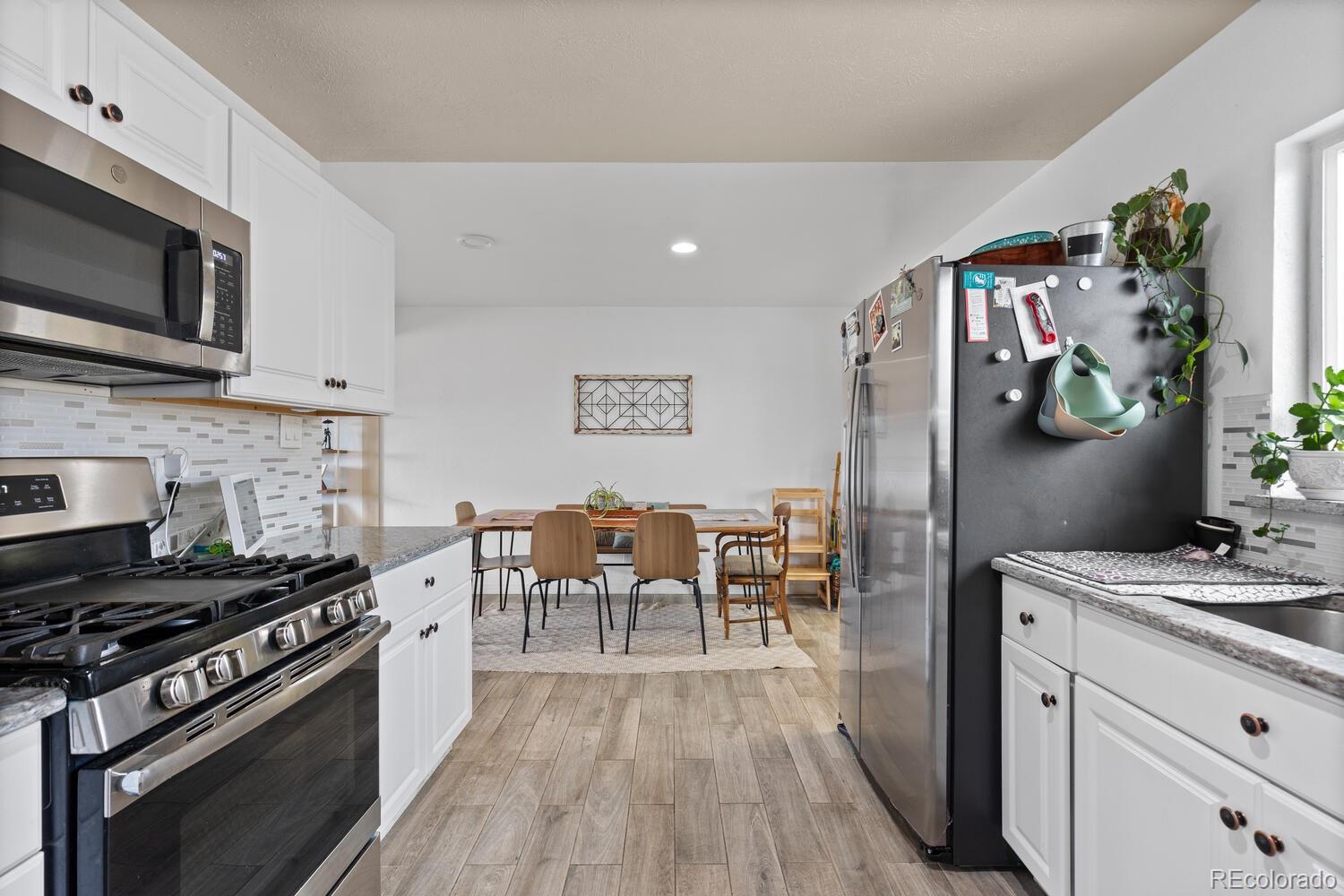 3106 South Wolff Street Denver, CO 80236 - Photo 37 of 48 a kitchen with stainless steel appliances granite countertop a stove top oven a sink dishwasher a dining table and chairs with wooden floor