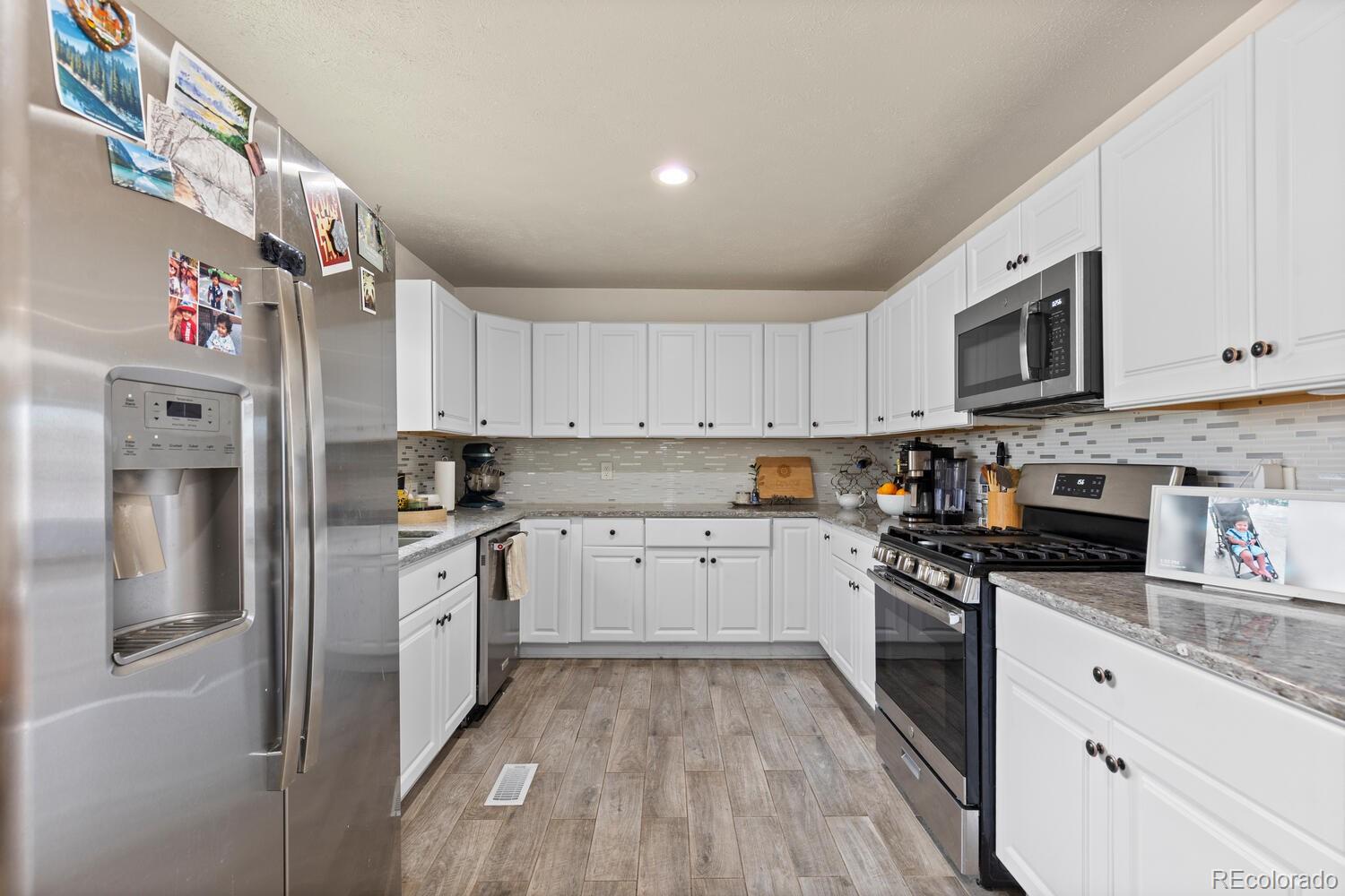 3106 South Wolff Street Denver, CO 80236 - Photo 7 of 48 a kitchen with stainless steel appliances granite countertop a stove a sink and a refrigerator