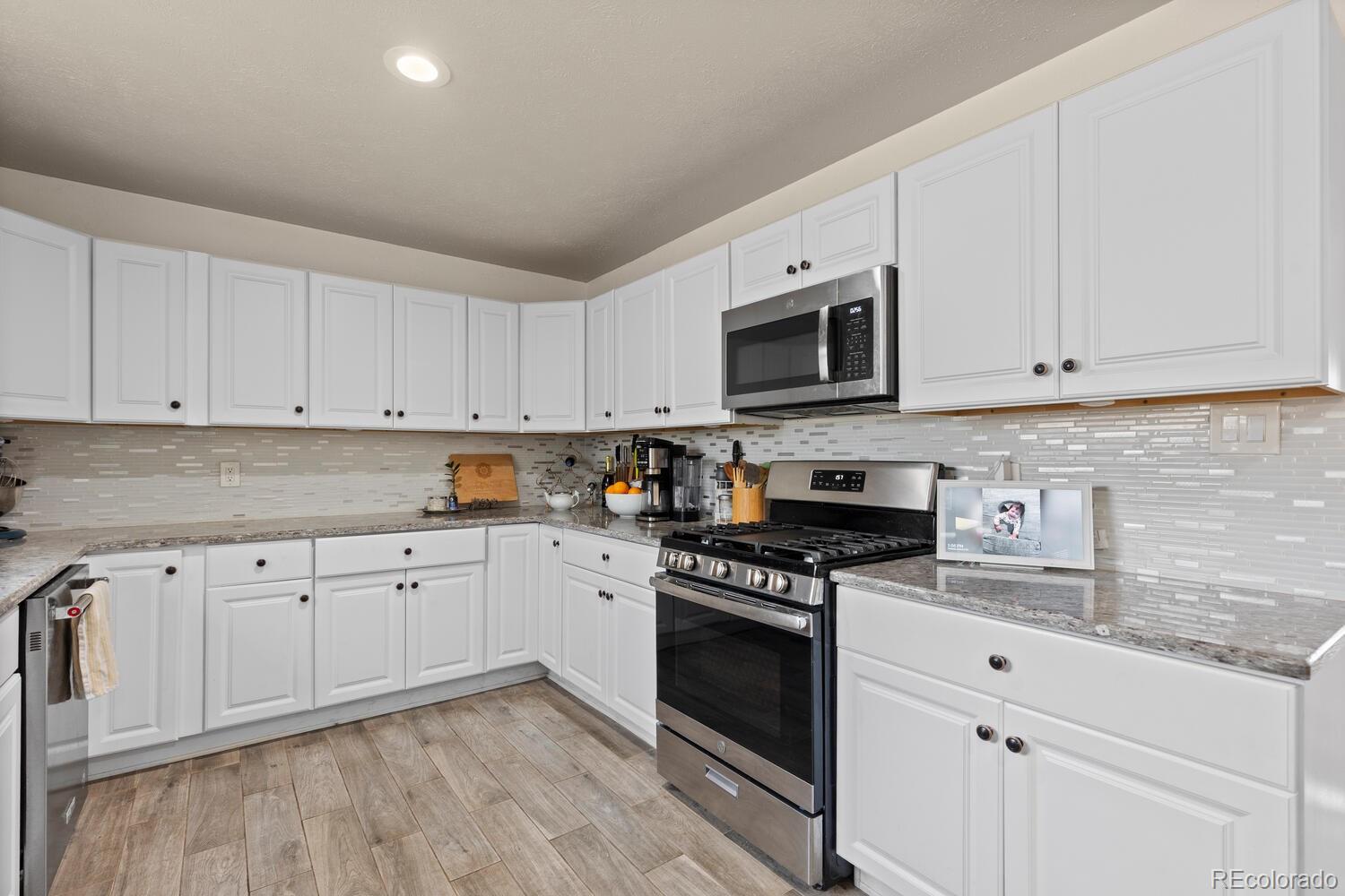 3106 South Wolff Street Denver, CO 80236 - Photo 9 of 48 a kitchen with granite countertop white cabinets sink and stainless steel appliances