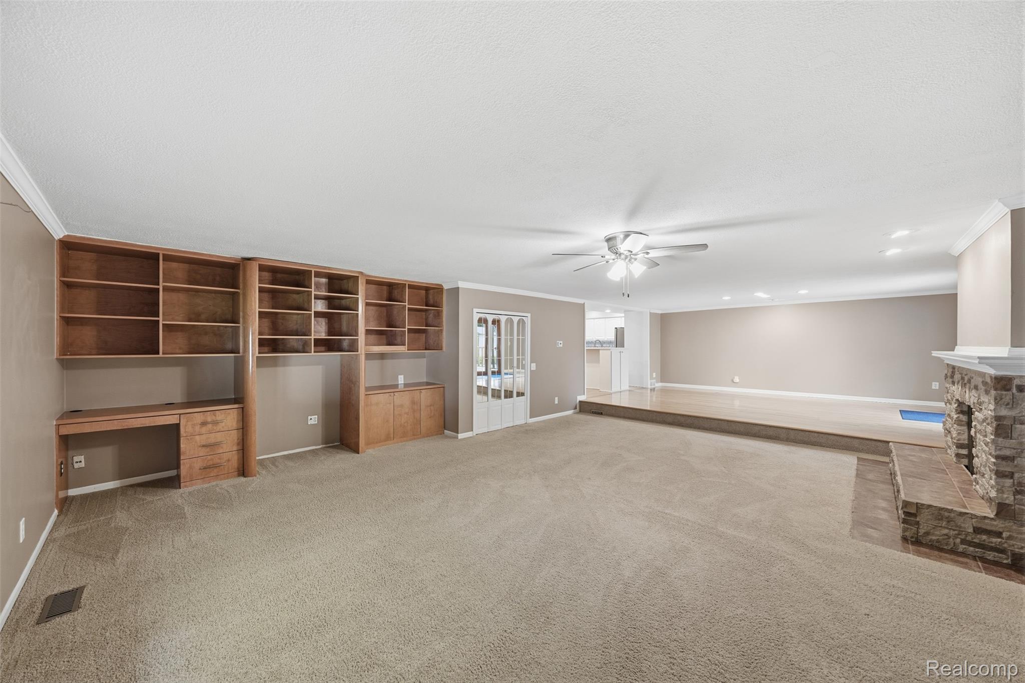 1087 Collingwood Drive Rochester, MI 48307 - Photo 25 of 56 Built-in shelving with integrated desk, stone-clad fireplace, ceiling fan, recessed lighting, and crown molding