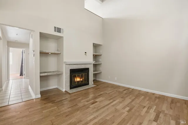 a view of empty room with wooden floor and fireplace