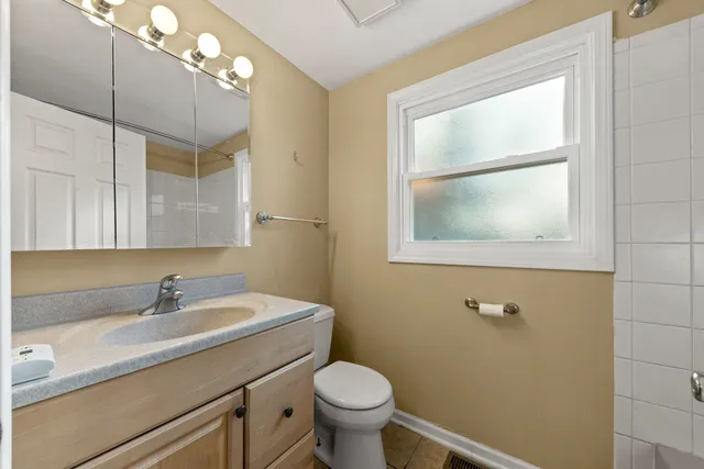 a bathroom with a toilet a sink a vanity and mirror
