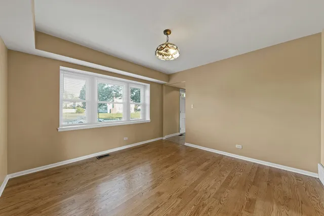 a view of an empty room with window and wooden floor