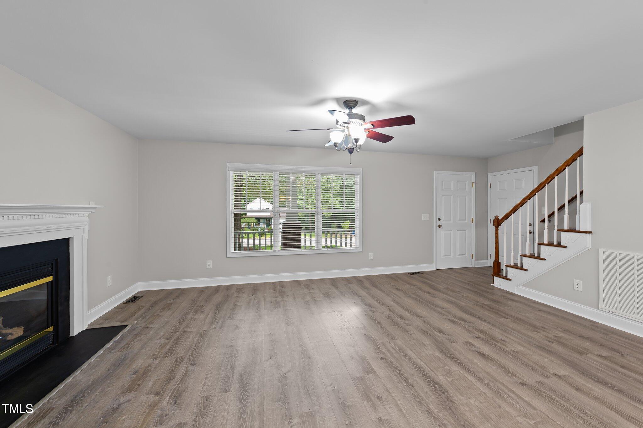 2713 Rustic Brick Road Raleigh, NC 27603 - Photo 8 of 53 a view of an empty room with wooden floor fireplace and a window