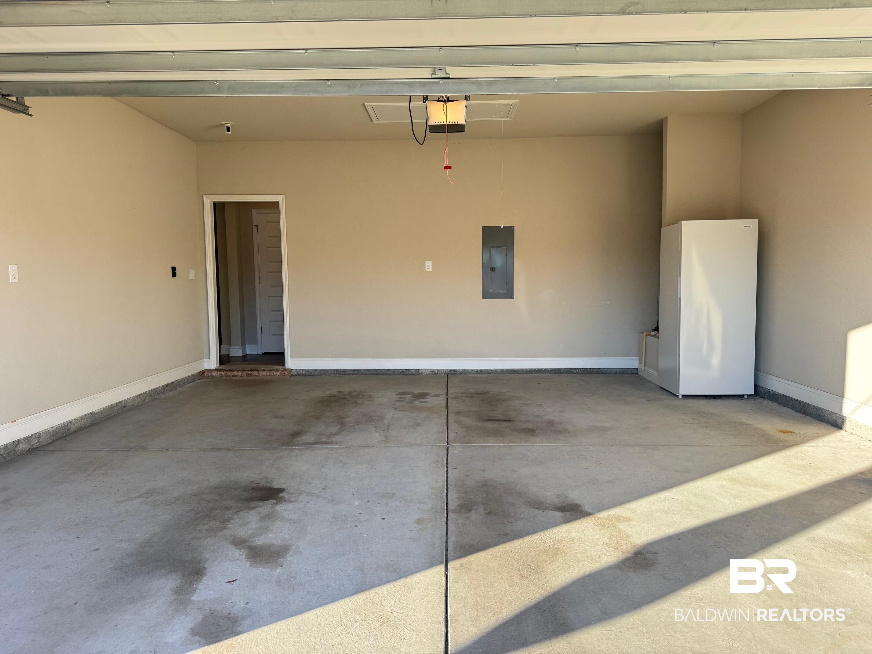 1346 Kairos Loop Foley, AL 36535 - Photo 36 of 40 Garage with white refrigerator, electric panel, and a garage door opener