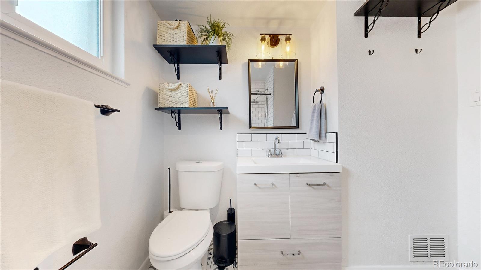 3155 Steele Street Denver, CO 80205 - Photo 13 of 37 a bathroom with a toilet a sink and mirror