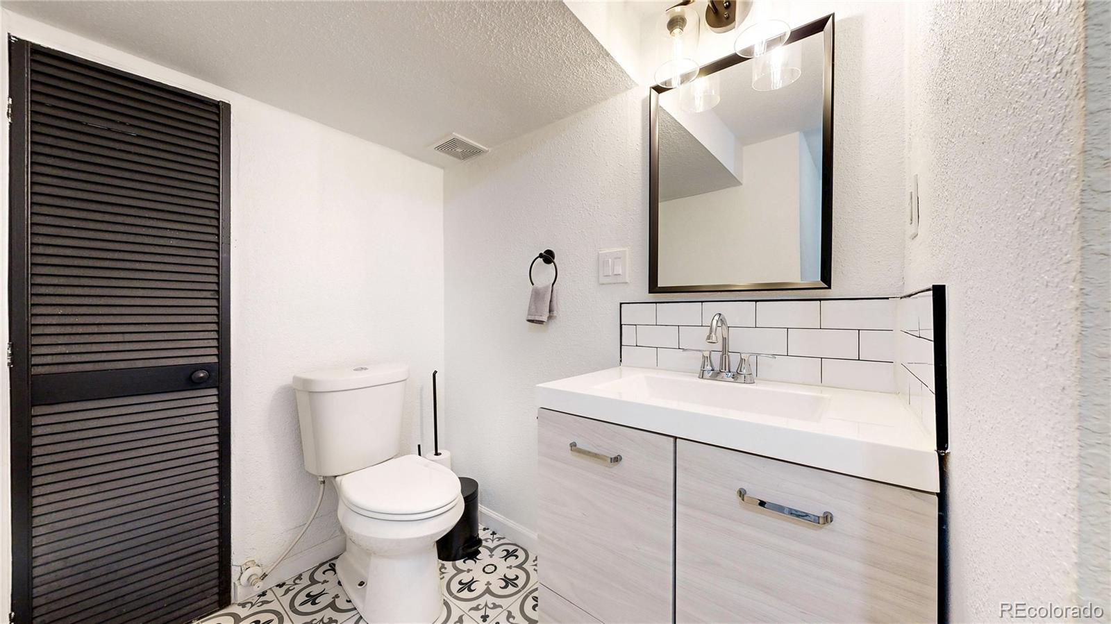 3155 Steele Street Denver, CO 80205 - Photo 24 of 37 a bathroom with a toilet a sink and mirror