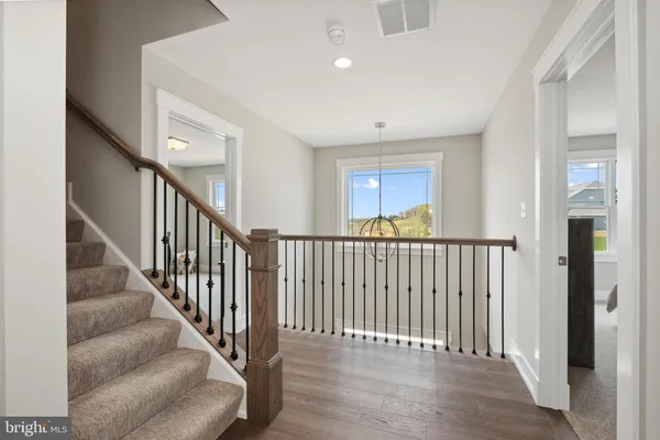 a view of a hallway with wooden floor and staircase