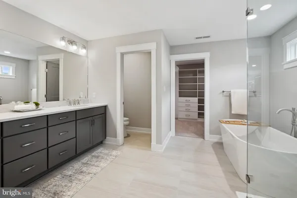 a spacious bathroom with a double vanity sink a large mirror and a bathtub