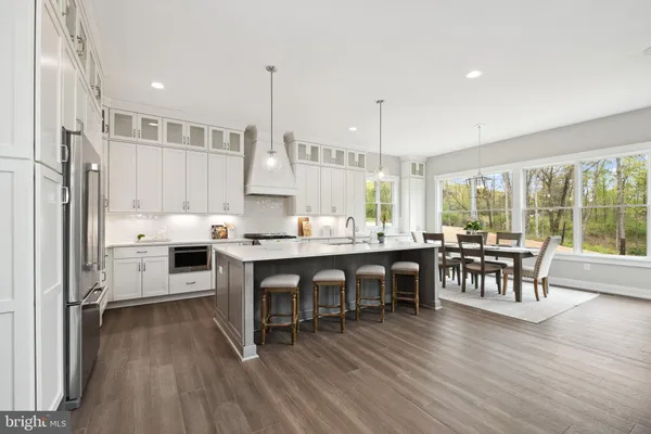 a kitchen with stainless steel appliances granite countertop a table chairs stove and wooden floor