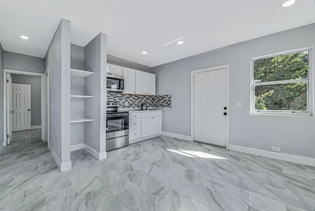 an empty room with cabinet and windows