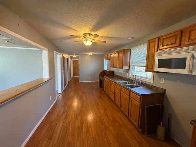 a kitchen with stainless steel appliances granite countertop a refrigerator a stove top oven a sink dishwasher and wooden cabinets with wooden floor