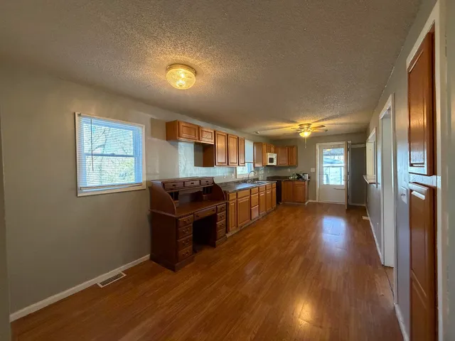 a living room with stainless steel appliances kitchen island granite countertop wooden floors and wide window