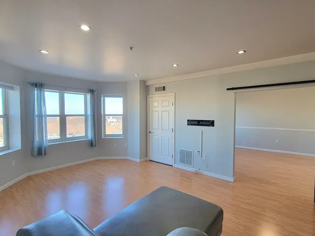 a view of an empty room with a window and wooden floor