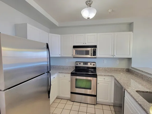 a kitchen with cabinets stainless steel appliances and a counter space