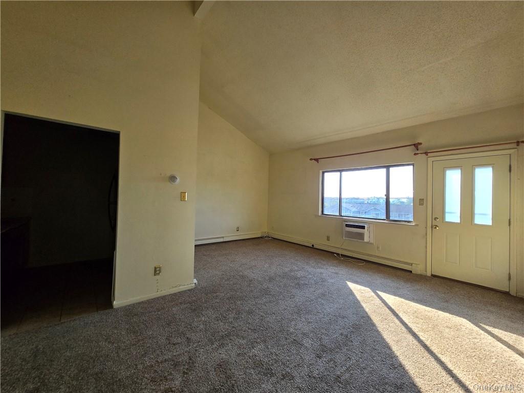 44 Inwood Road Middletown, NY 10941 - Photo 3 of 15 Carpeted spare room featuring a wall mounted AC, high vaulted ceiling, and a textured ceiling