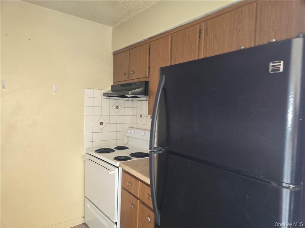 44 Inwood Road Middletown, NY 10941 - Photo 7 of 15 Kitchen featuring electric range, black refrigerator, tasteful backsplash, and a textured ceiling
