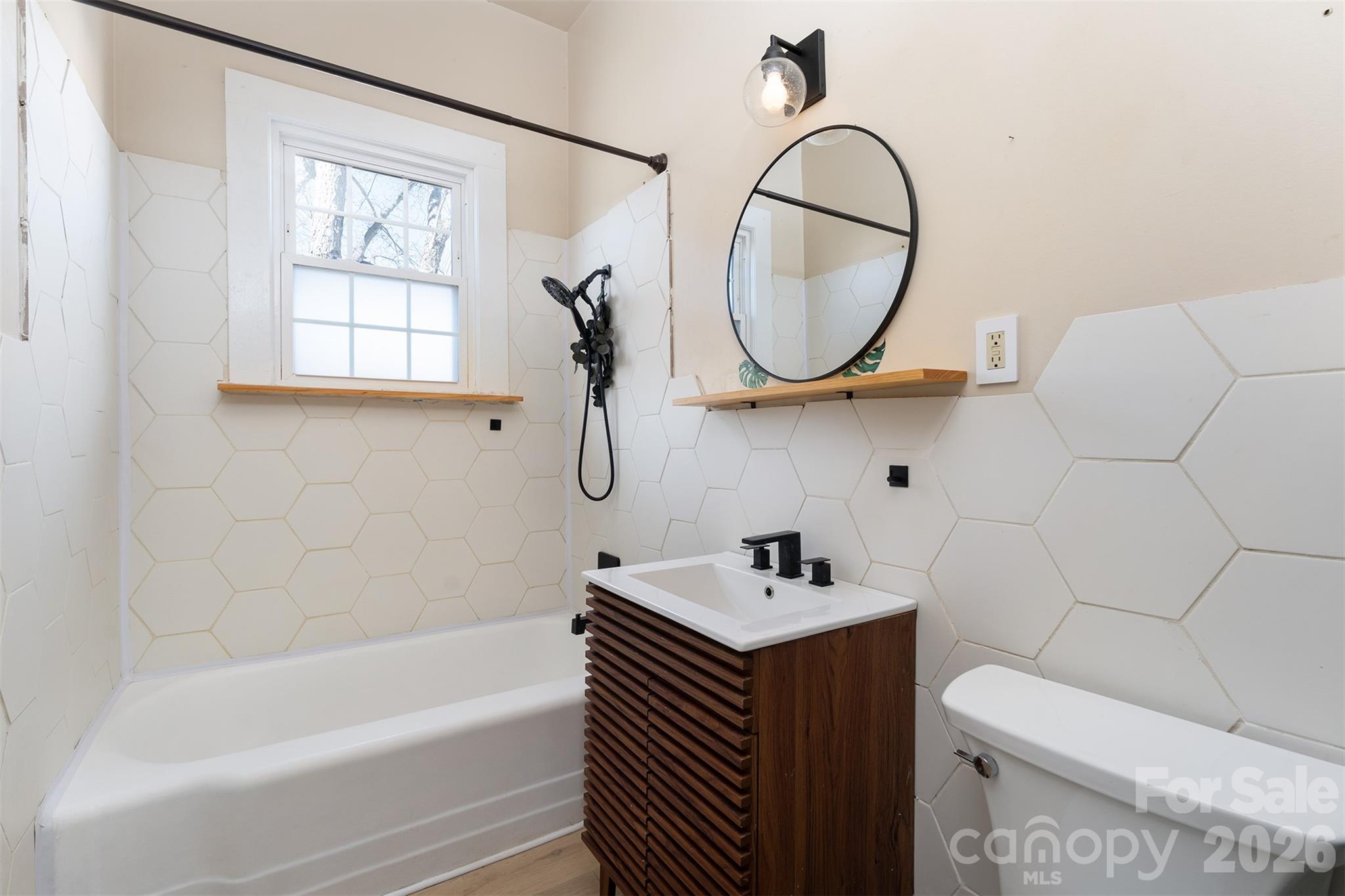 20 1st Street Marion, NC 28752 - Photo 7 of 23 a bathroom with a sink a mirror a toilet and a bathtub