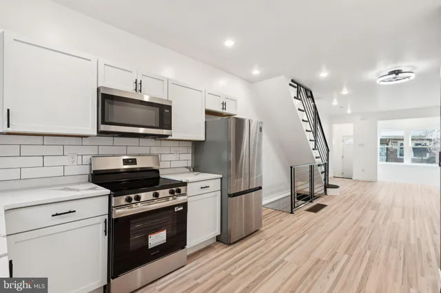 a kitchen with a appliances a sink dishwasher a refrigerator and a stove top oven