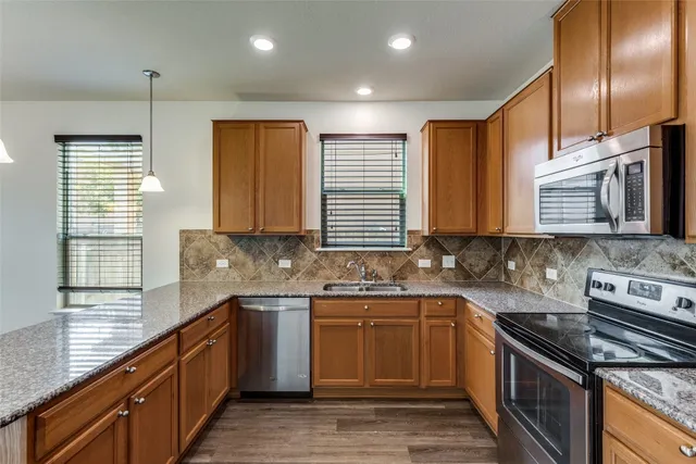 a kitchen with stainless steel appliances granite countertop a sink a stove counter space and cabinets