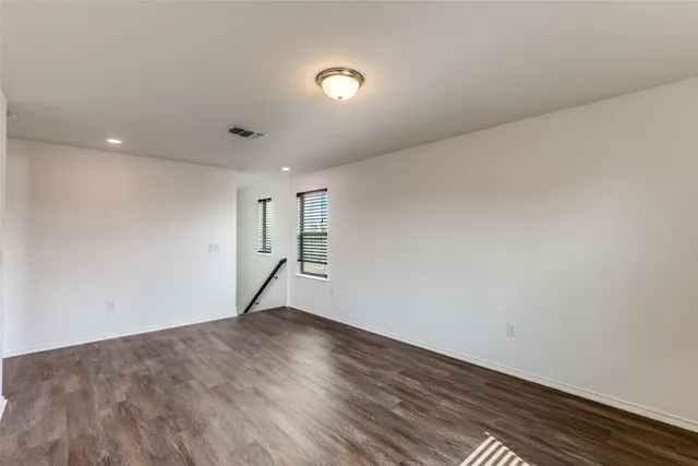 an empty room with wooden floor chandelier fan and windows