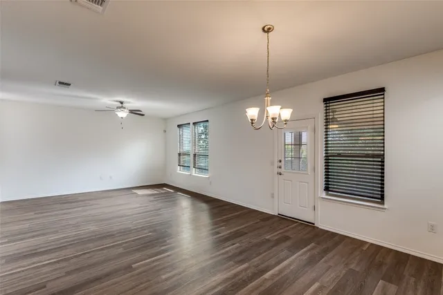 a view of a room with wooden floor ceiling fan and windows