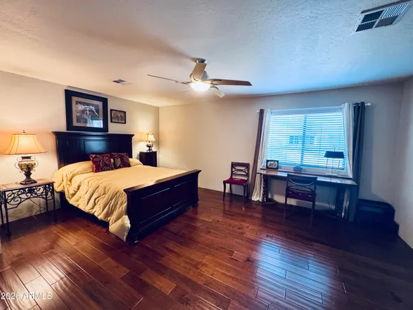 a bedroom with a large bed a chandelier and wooden floor
