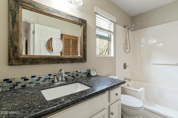 a bathroom with a granite countertop sink mirror vanity and toilet
