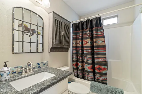 a bathroom with a granite countertop sink a toilet and shower