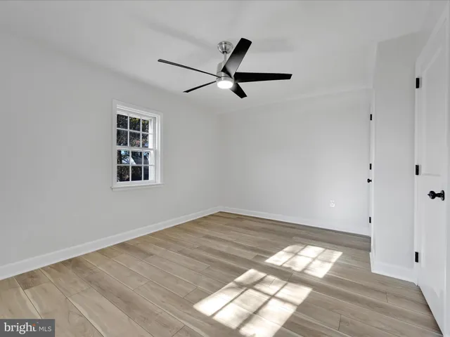 a view of empty room with wooden floor and window
