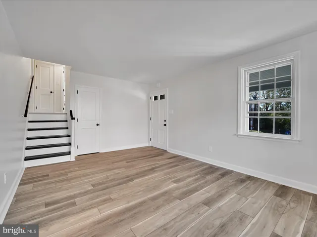 a view of an empty room with wooden floor and windows