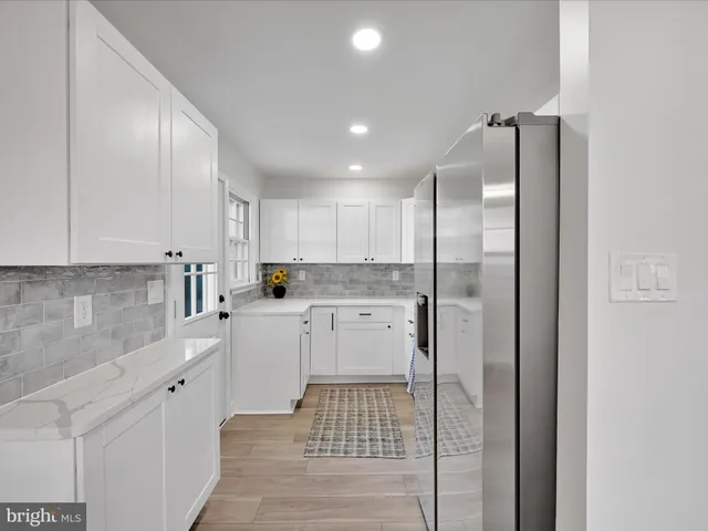 a kitchen with a refrigerator and white cabinets
