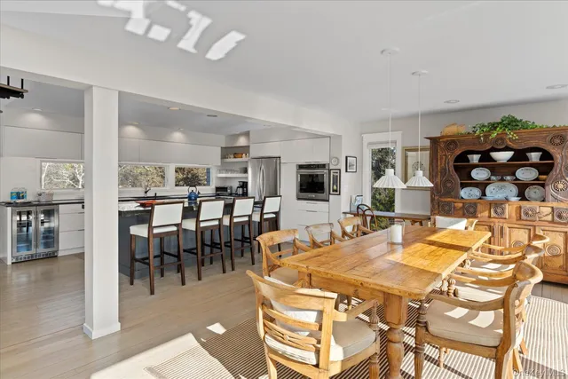 a dining hall with stainless steel appliances kitchen island a table and chairs in it