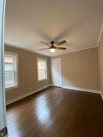 an empty room with wooden floor fan and windows