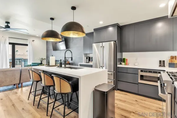 a kitchen with stainless steel appliances a stove a sink a refrigerator and chairs