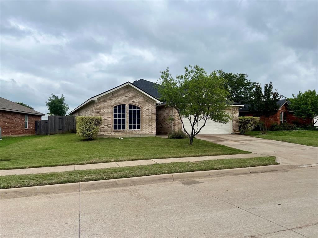 12201 Rolling Ridge Drive Fort Worth, TX 76028 - Photo 1 of 21 Brick facade residence featuring an arched window, attached two-car garage, concrete driveway, and established landscaping with mature trees