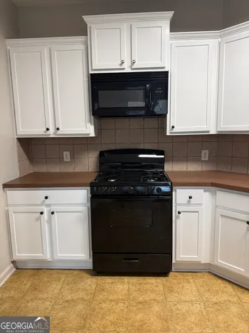 a kitchen with granite countertop white cabinets and black appliances